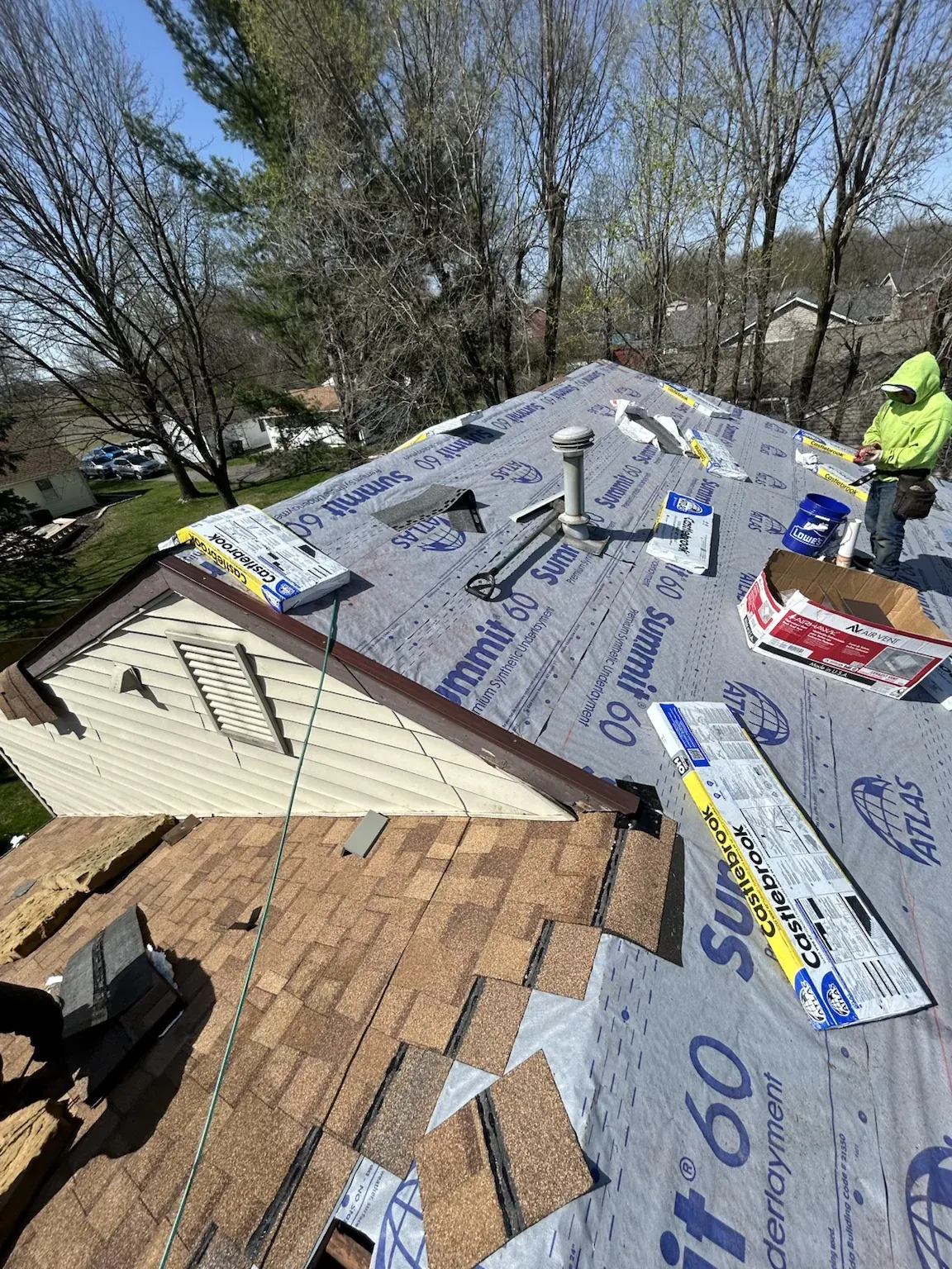 Atlas Summit 60 synthetic underlayment going down as the old brown shingles come off, with a pipe vent and new materials on the roof